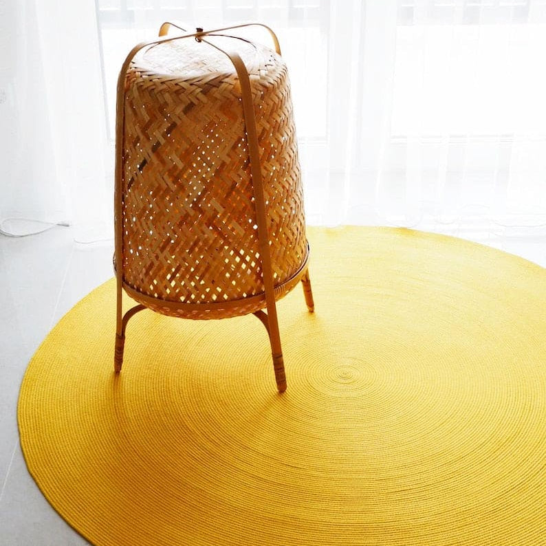 Yellow round rug with a woven basket on a white background