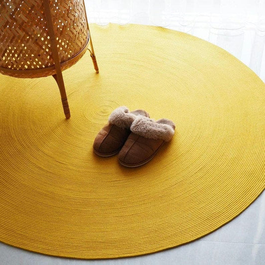 Yellow round rug with a woven chair and slippers on a light background